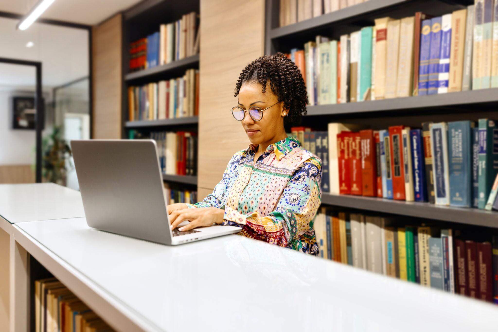 An educator working on a laptop in a library